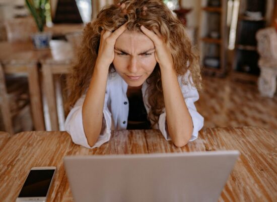 photo of woman leaning on wooden table while looking upset